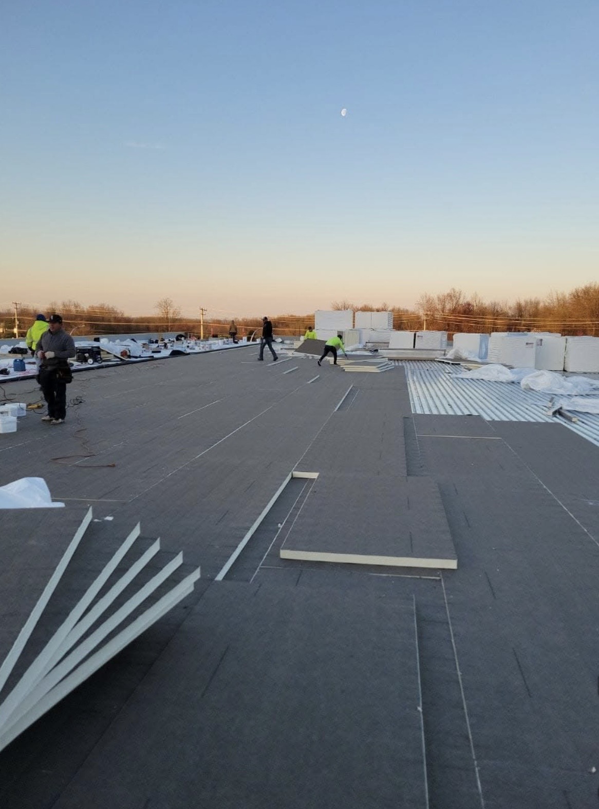 Pioneer crew installing insulation and membrane on a large commercial flat roof in New Jersey