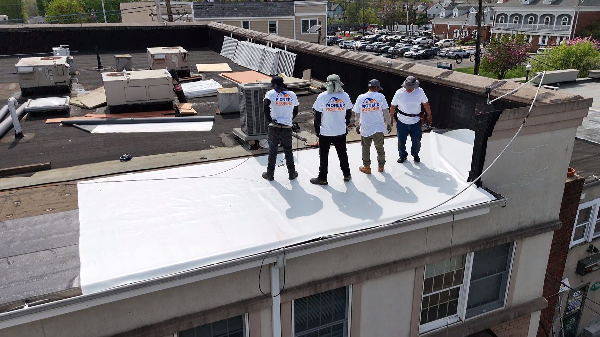 Pioneer Roofing crew on a completed white TPO flat roof above a downtown New Jersey storefront